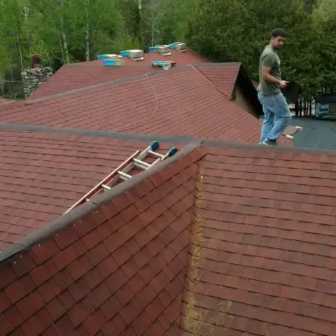 Red asphalt shingle roof with a Star Boy Roofing crew member walking the ridge