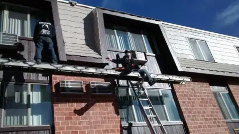 Crew working on the mansard roof of a two-story commercial building