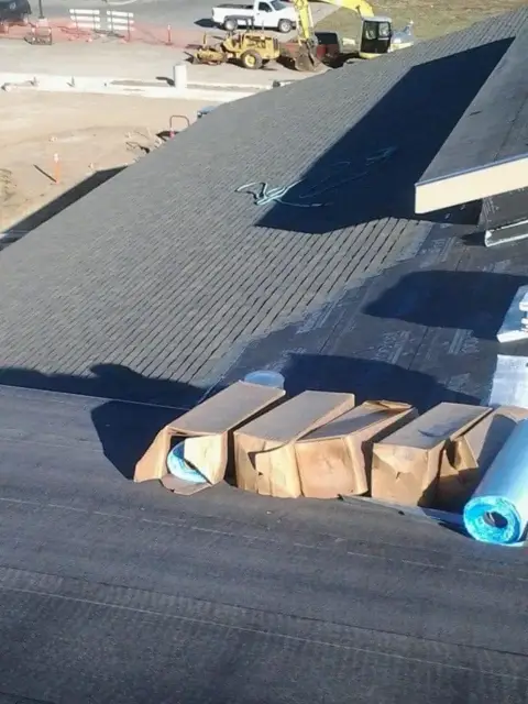Shingle bundles laid out across a roof covered in new underlayment