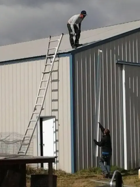Crew installing trim on a steel building