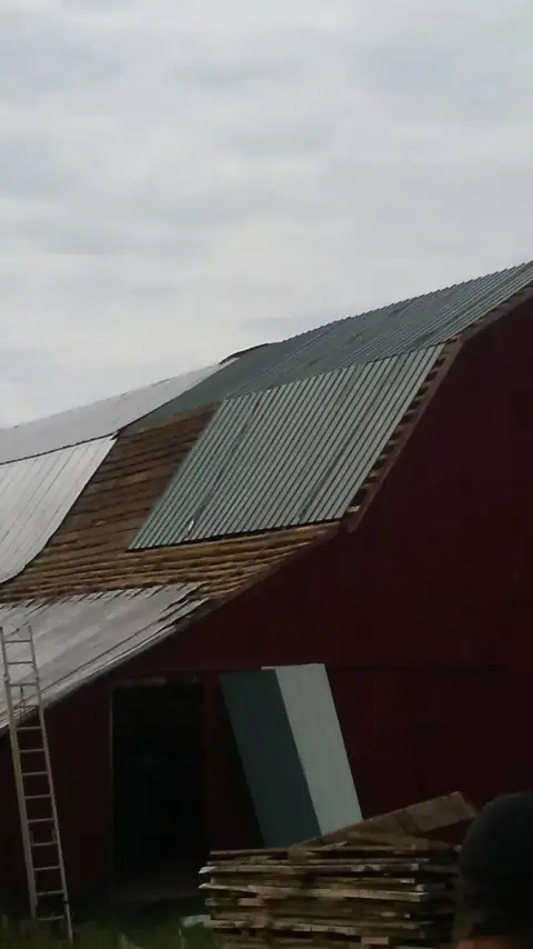 Barn roof half stripped, with new metal panels going on