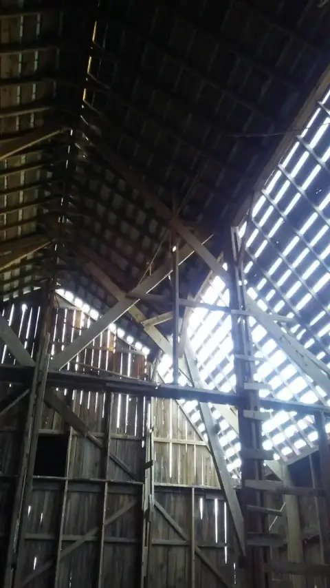 Daylight through the old roof boards inside a barn before the re-roof